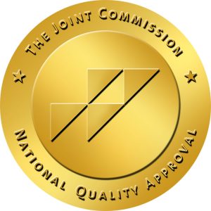 Gold circular seal with black diagonal lines and a geometric design in the center, surrounded by the text 
